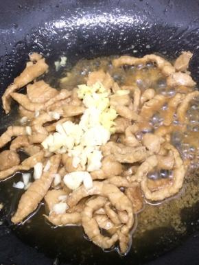 在把大蒜和生姜粒放入锅中，炒出香味