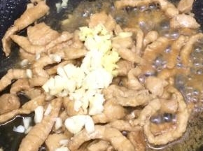 在把大蒜和生姜粒放入锅中，炒出香味