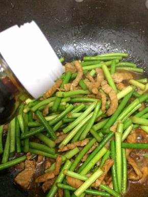 再倒入少许的生抽翻炒，直到蒜苔变软