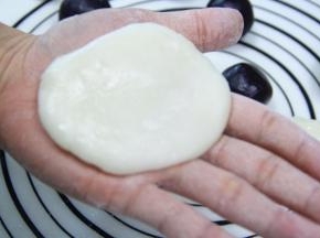 手上沾少许糕粉防粘，将25克的冰皮放在手心压扁。