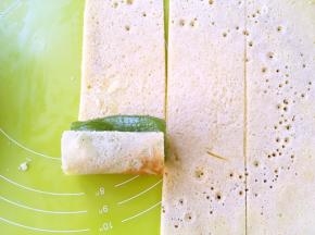 取一个奇异果放在一片蛋糕片上卷起来，顺着奇异果的圆弧卷紧