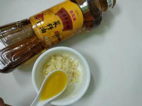 大蒜装入碗里加入一勺金龙鱼菜籽油。
