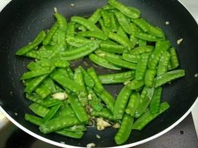 倒入荷兰豆快速翻炒均匀，加入少量清水（10毫升）加盖焖煮一会儿，继续翻炒至荷兰豆快熟。