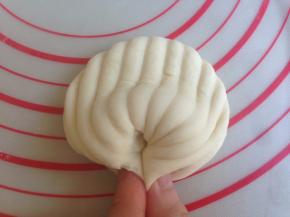 将中间凸出的部位向下按一下，两端要捏紧，否则蒸好的时候会裂开