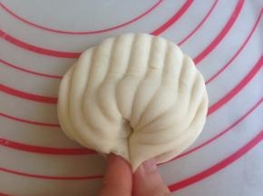 将中间凸出的部位向下按一下，两端要捏紧，否则蒸好的时候会裂开