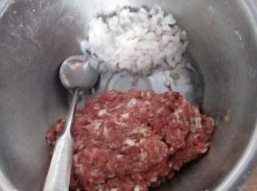 搅拌上劲儿的牛肉馅扒到一边，洋葱碎大约70克，先用香油拌均匀，这样可以锁住洋葱的水分