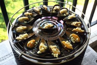 烧烤炉起炉火后，将海虹排放到烤网上，给每一个海虹抹油并撒上蒜粒。