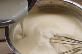 从边缘倒入乳化好的第二步「牛奶」，继续用打蛋器打五圈左右，让它们混合均匀「此时会有少许消泡，正常。」