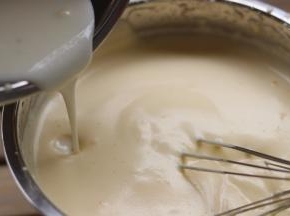 从边缘倒入乳化好的第二步「牛奶」，继续用打蛋器打五圈左右，让它们混合均匀「此时会有少许消泡，正常。」