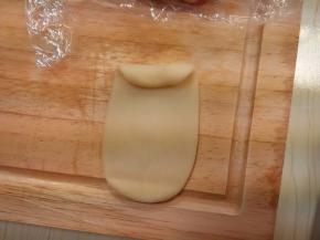 擀开成一个牛舌状（擀时要轻点），由上往下卷起来；再擀开，卷起。用同样的方法把红色水油皮做好；