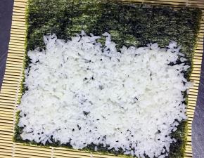 将米饭平铺于海苔上 最上面留出1-2cm