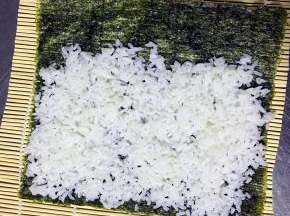 将米饭平铺于海苔上 最上面留出1-2cm