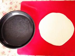 排气后，擀成披萨盘大小的圆盘，披萨盘抹黄油，