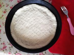 放入披萨盘里，用叉子在饼皮上扎孔排气，