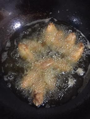 锅烧热倒入适量的油烧至七成热，放入腌制好的鸡翅中小火慢慢的炸，边炸边用筷子搅拌一下，别粘锅了！