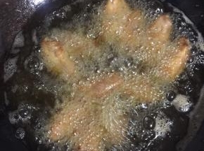 锅烧热倒入适量的油烧至七成热，放入腌制好的鸡翅中小火慢慢的炸，边炸边用筷子搅拌一下，别粘锅了！