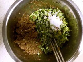 8.把肉馅放到盆的一边，倒入解冻后的槐花，槐花里加入适量花生油，盐，酱油，十三香及香油，将槐花和调料搅拌均匀