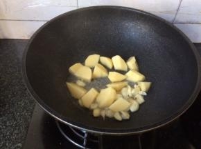 锅中热油，放入蒜瓣爆香，加入土豆