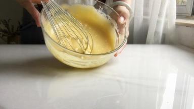 6 加入蛋黄，拌匀，盖上保鲜膜备用
用蛋抽画1字，挑起蛋黄糊，让她自由的滴落，混合的更均匀
最后取抹刀，把蛋盆边缘部分刮进去，拌匀