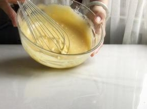 6 加入蛋黄，拌匀，盖上保鲜膜备用
用蛋抽画1字，挑起蛋黄糊，让她自由的滴落，混合的更均匀
最后取抹刀，把蛋盆边缘部分刮进去，拌匀