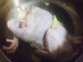 烧一锅清水，加入适当姜片、料酒，水开后放入清洗干净的整鸡，烫至表皮收紧立即捞出放入冰水中冷却。然后再次放入沸水中小火煮25分钟
