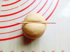 揉圆的面团整理一下，利用牙签压出南瓜的纹路，首先牙签再面团顶端中间处压一下印痕，如图。