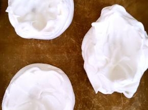 烤盘铺油纸，将蛋白装入裱花袋，挤出三份圆形，用勺背在中间转圈抹一下，抹出碗的形状即可，烤箱预热130度烤60分钟