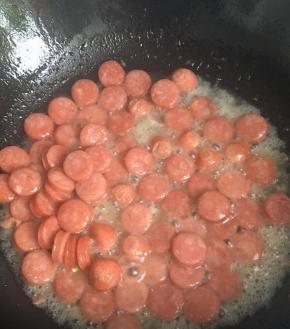 把白糖水倒入锅中，这样白糖的一点甜味，加入了温开水烤肠的口感会比较软弹不会发硬，水量沫过烤肠底部即可，继续翻炒