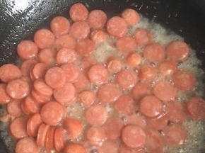 把白糖水倒入锅中，这样白糖的一点甜味，加入了温开水烤肠的口感会比较软弹不会发硬，水量沫过烤肠底部即可，继续翻炒