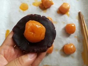 取一个豆沙馅球按扁包上蛋黄
