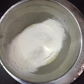 将低粉，泡打粉，盐混合过筛加入鸡蛋液中，搅拌至没有颗粒。