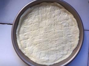 将面团擀出形状后放入披萨盘中，用叉子叉出小洞，这样避免饼皮烤时膨胀太高