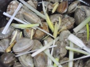 将蛤蜊一个个的夹进砂锅里，上面撒上葱姜丝，这个时候再开火。