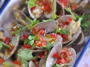 将蛤蜊一个个夹出来放入盘中，浇上酱料，最后撒上香菜。