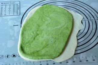 抹茶面团也擀成一张小于白面皮的面皮，铺在白色面皮上。