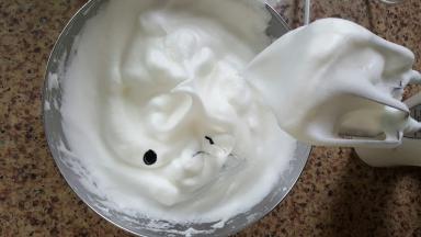 13．打好的蛋白霜提起打蛋头，形成一个小的弯钩，加入一滴黑色色素搅匀。