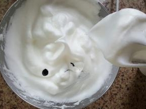 13．打好的蛋白霜提起打蛋头，形成一个小的弯钩，加入一滴黑色色素搅匀。