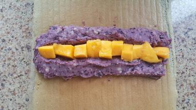 23．中间放上切好的芒果颗粒，用擀面杖辅助蛋糕卷卷好。