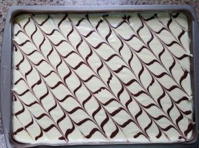 7. 将蛋卷糊从稍高处倒入烤盘中，可以消除大的气泡，刮平，裱花袋剪个小孔，在面糊上画上均匀的横线，再用牙签拉上来回的竖线。