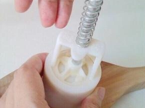 10、月饼胚稍搓成柱型，放入模具，一手扶模具下端，另一手果断用力向下压，然后提起模具，向下轻压，月饼出。 