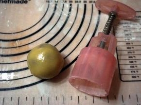 将面团压开后包裹好馅料，滚圆，拍粉，放入模具中。