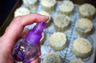 在月饼表面喷洒少许清水，放入预热好的烤箱中层，上下火210度烘烤8分钟定型。