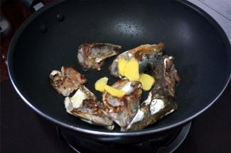 再将锅里的鱼头翻转，加入姜片。