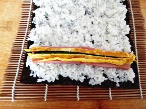 在靠近紫菜的一头摆好黄瓜，火腿和鸡蛋皮，