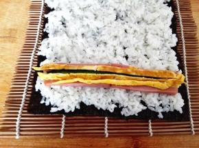 在靠近紫菜的一头摆好黄瓜，火腿和鸡蛋皮，