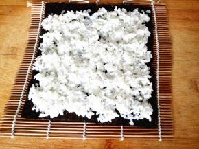 紫菜平铺在寿司卷帘上，上面铺上米饭，注意一定要均匀，这样做出来的寿司才漂亮