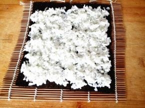 紫菜平铺在寿司卷帘上，上面铺上米饭，注意一定要均匀，这样做出来的寿司才漂亮