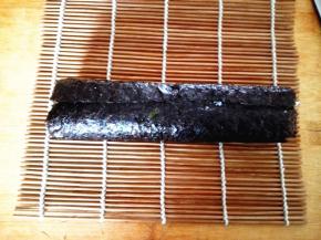 用寿司帘将其卷起，注意要卷得紧一些，这样切出来的寿司才漂亮，