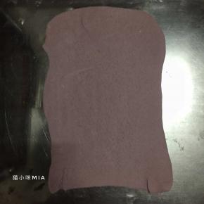 将紫薯面团擀开，呈长方形片状，表面刷少许清水