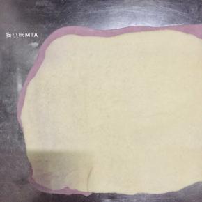 铺上同样擀成长方形片状的白色面团，再用擀面杖压一遍，使两种面团完全贴合